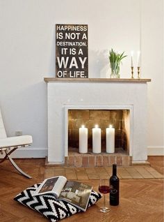 a living room with a fire place and some candles on the floor next to it