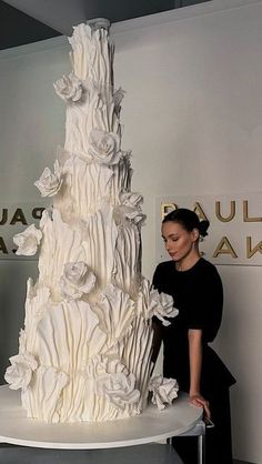 a woman standing next to a large white cake