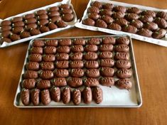 three trays filled with chocolate covered cookies on top of a wooden table