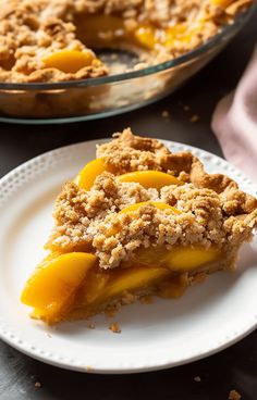 a slice of peach pie on a plate with another pie in the backround