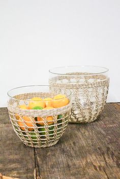 two glass bowls filled with fruit sitting on top of a wooden table next to each other