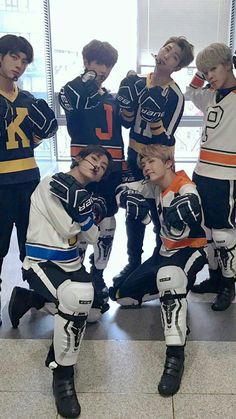 the young men are posing for a photo in their hockey uniforms and helmets, with one holding his hand on his face