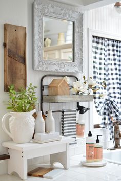 a white table topped with vases filled with flowers and other items next to a mirror