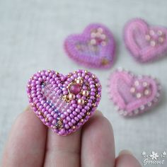 the beaded heart is being held in someone's hand with other beads around it