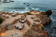 an outdoor dining area with tables and chairs near the ocean