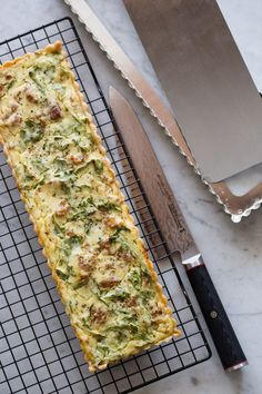 a long piece of food sitting on top of a cooling rack next to a knife