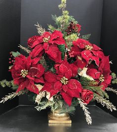 a vase filled with red poinsettias and greenery