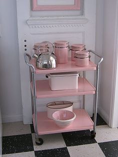 a pink shelf with dishes on it in front of a white door and black and white checkered floor