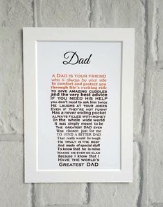 a white frame hanging on a brick wall with the words dad written in orange and black