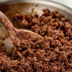 a close up of food in a pan with a wooden spoon