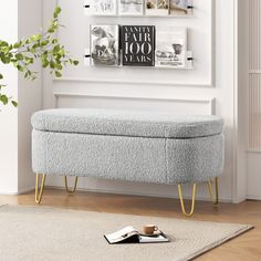 a gray bench sitting on top of a wooden floor next to a wall mounted book shelf