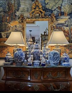 blue and white vases are sitting on a dresser in front of a large mirror