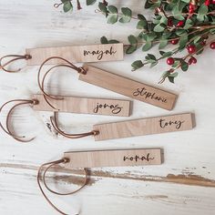 four wooden name tags with names hanging from them on a white table next to berries