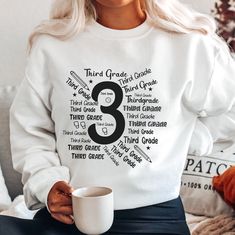 a woman sitting on a couch holding a coffee mug with the number three printed on it