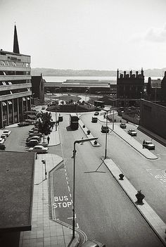 an aerial view of a city street with cars driving on the road and buildings in the background