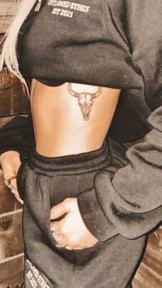 a woman with tattoos on her stomach wearing a black hoodie