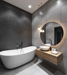 a large white bath tub sitting next to a sink in a bathroom under a round mirror