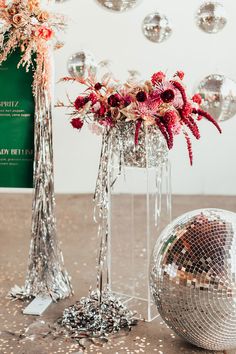 a disco ball and vase with flowers in it on the floor next to a mirror ball