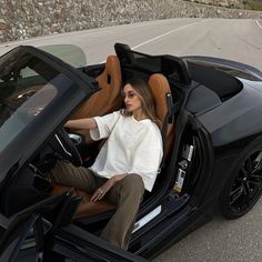 a woman sitting in the driver's seat of a sports car