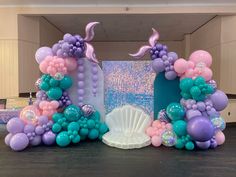 the balloon arch is decorated with mermaid balloons and seashells