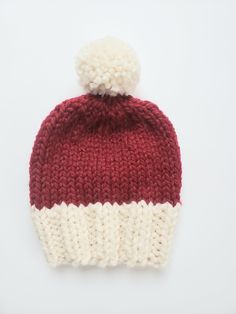 a red and white knitted hat with a pom - pom