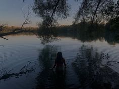 a woman wading in the water at sunset