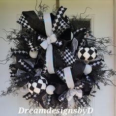 a black and white wreath with checkered balls hanging on the front door for halloween