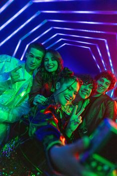 a group of young people standing next to each other in a room with neon lights