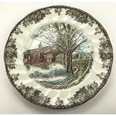 a decorative plate with a farm scene painted on the side and trees in the middle