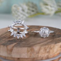 two diamond rings sitting on top of a wooden board next to each other, with flowers in the background