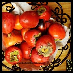 a bowl filled with red tomatoes on top of a wooden table