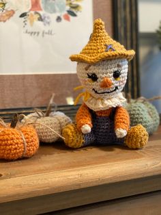 a crocheted cat sitting on top of a wooden table next to pumpkins