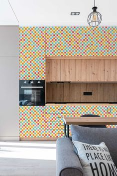 a living room filled with furniture next to a wall covered in multicolored tiles