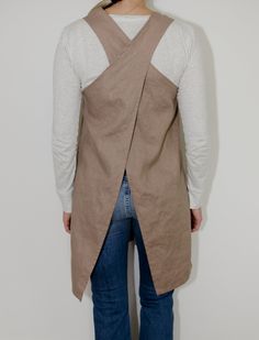 the back of a woman wearing a tan vest with an asymmetrical design