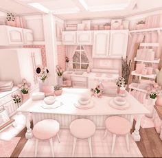 a pink kitchen with lots of white furniture and flowers in vases on the table