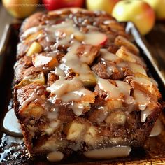 a loaf of cinnamon apple bread with icing and apples in the background