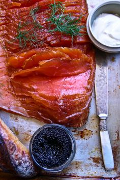 raw salmon and other ingredients on a baking sheet with knife, fork and spoon next to it