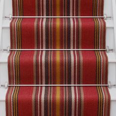 red and yellow striped carpeted stairs leading up to the second floor with white handrails