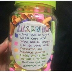 a person holding a jar filled with lots of colorful beads and writing on the label