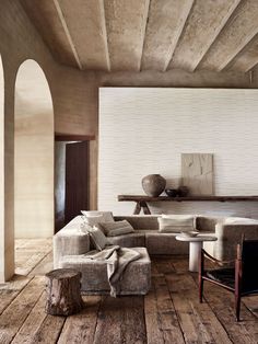 a living room filled with furniture and wooden flooring next to a white brick wall