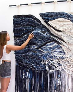 a woman standing next to a large piece of art made out of yarn and beads