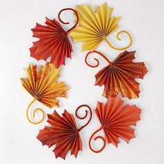 four red, yellow and orange paper leaves are arranged in a spiral pattern on a white background