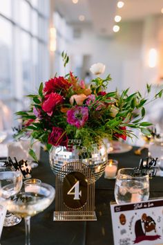 the table is set with wine glasses, flowers and place cards for guests to sit at