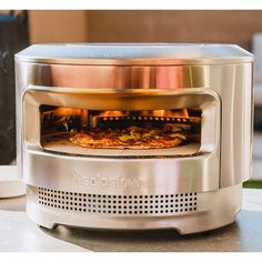 a pizza is cooking in an oven on the counter top next to a coffee mug