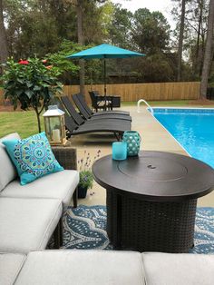 an outdoor living area with couches, table and umbrella next to a swimming pool