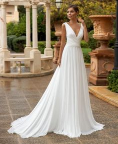 a woman in a white wedding dress posing for the camera with her hand on her hip