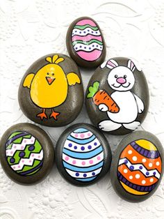 six painted rocks with easter eggs and animals on them, all decorated in different colors