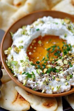 a bowl filled with hummus and sauce on top of pita chips