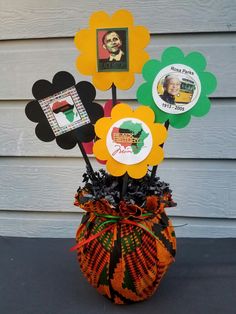 a vase filled with flowers and pictures on top of a black table next to a wall