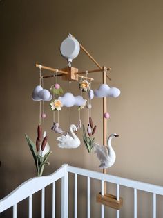 a baby crib with some birds hanging from it's hooks and flowers on the rails